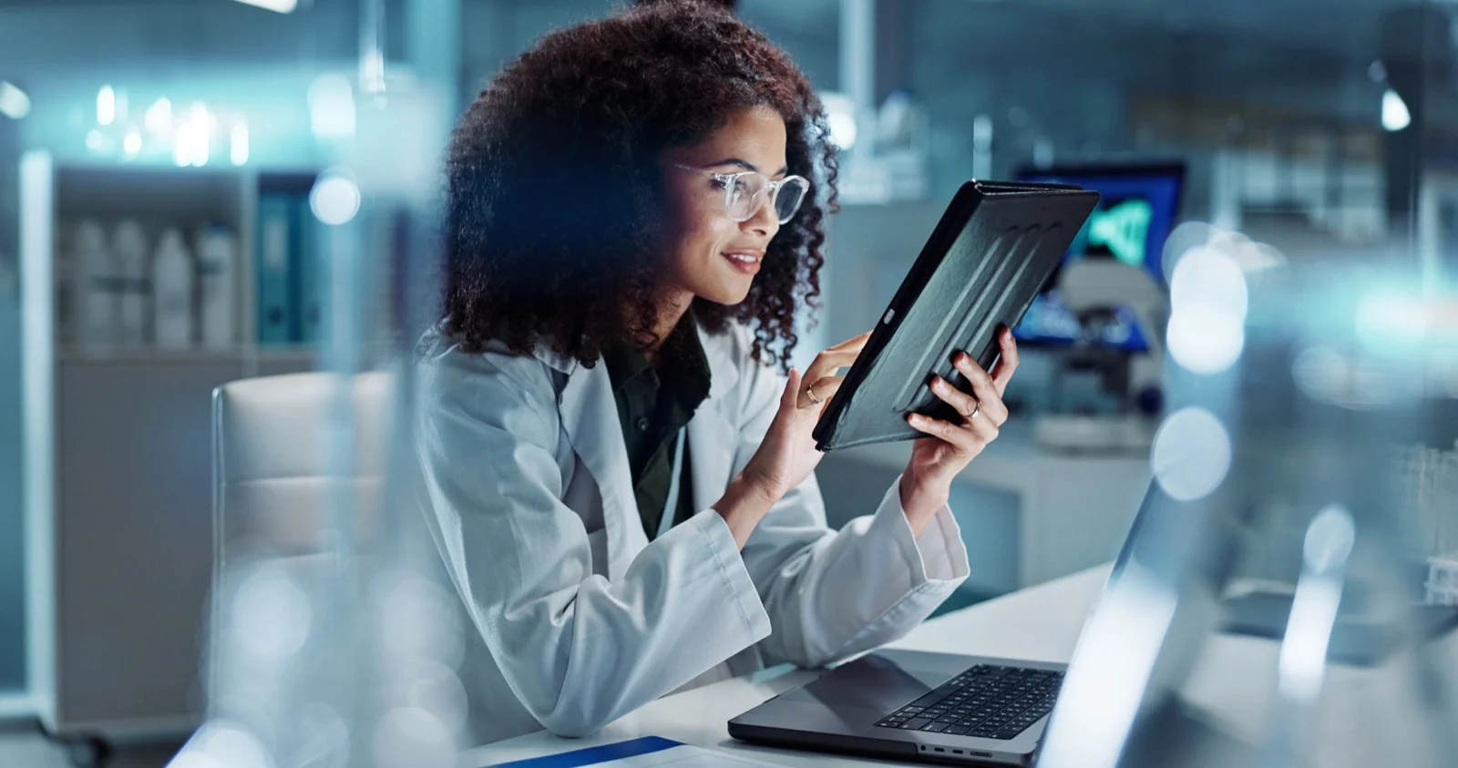 Researcher working on a tablet and laptop in a lab