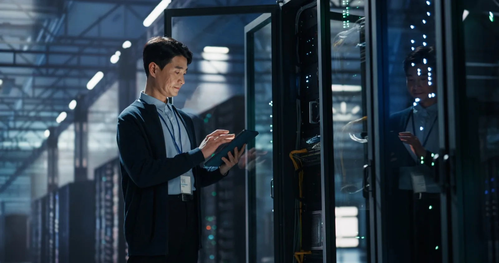 Engineer with a tablet working beside open server racks in a data centre