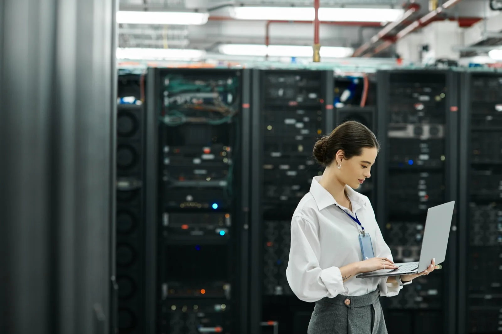 Data centre engineer working on a laptop beside rows of server racks