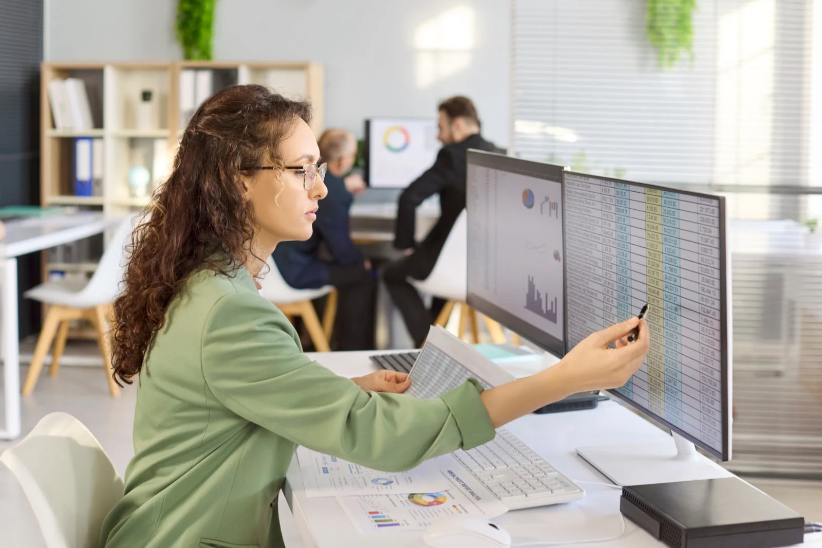 Analyst reviewing a large data table and charts across two monitors