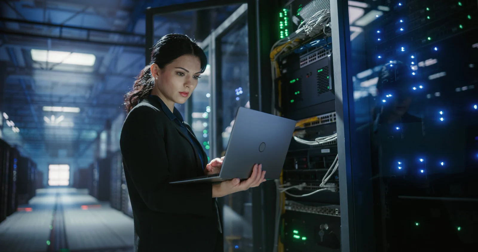 Engineer working on a laptop beside server racks in a data center